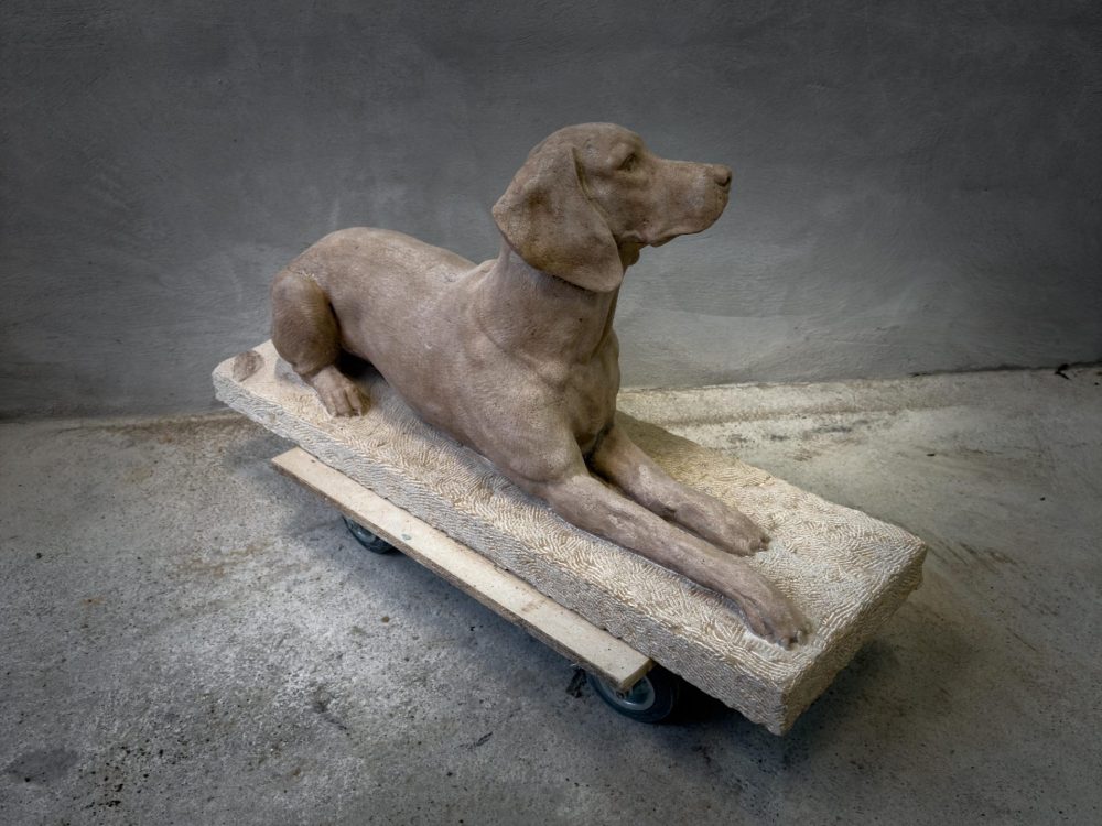 Chien couché sculpté dans la pierre Chien couché sculpté dans la pierre